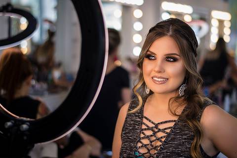 Moça maquiada para sua formatura em frente a um Ring Light'