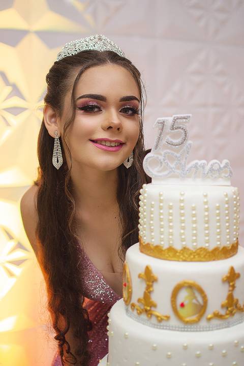 Debutante posa ao lado do bolo'