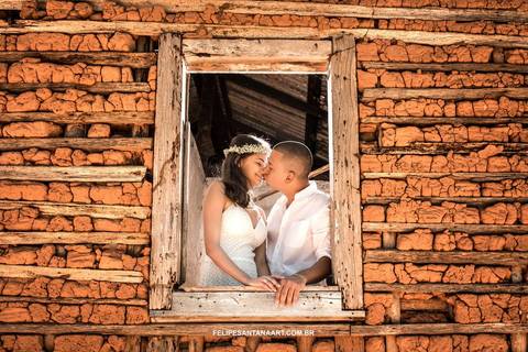 fotografia de casal se beijando na janela de uma casa velha'