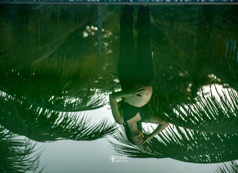 Fotografia de reflexo na água, gestante com a mão na barriga '