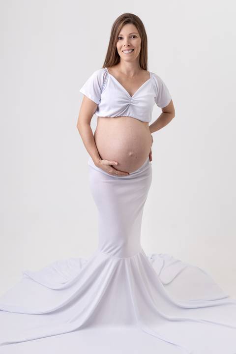 Gestante de 9 meses com vestido branco em ensaio em estúdio com o fundo branco ensaio fotógrafo Ander Lopes em Taquara/RS'