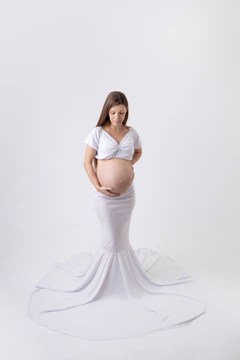 Gestante de 9 meses com vestido branco em ensaio em estúdio com o fundo branco ensaio fotógrafo Ander Lopes em Taquara/RS'