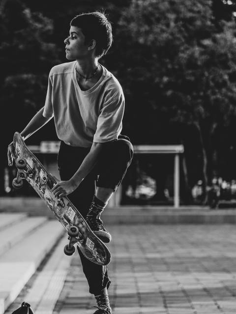Skatista segurando skate enquanto foca na sua direita em praça Cívica em Goiânia'