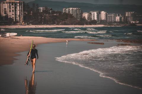 Surfista andando em praia segurando prancha de surf em praia da australia'