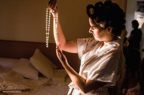 Detalhe emocionante da noiva com o terço em mãos, com a luz natural entrando pela janela no Hotel Plaza, Itu.'