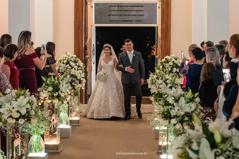 Portas abertas: noiva Gabriela de braços dados com o pai no corredor da Igreja do Quartel em Itu.'
