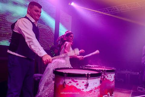 Momento animado dos noivos Gabriela e Guilherme tocando juntos no show de percussão iluminada na festa de casamento em Itu.'