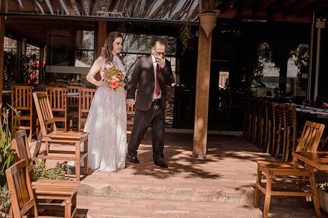 Um momento emocionante: a noiva caminha de mãos dadas com o pai em direção ao altar, simbolizando amor e tradição.'