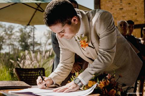 O noivo assina o registro do casamento, oficializando um dos momentos mais marcantes da cerimônia.'