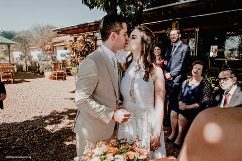 Após a formalidade da assinatura, os noivos se beijam e compartilham a alegria do momento com os convidados.'