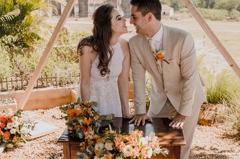 O casal troca olhares cheios de amor em frente ao altar decorado no Villa Itália, Piracicaba.'