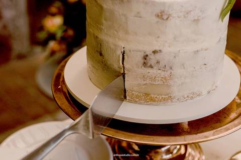O corte revela as primeiras camadas do bolo simples e elegante, parte de uma celebração leve e inesquecível.'