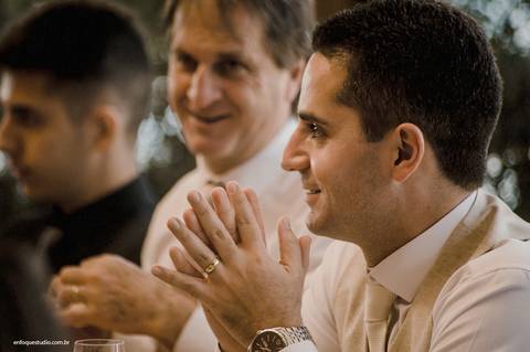 Entre risos e aplausos, o noivo participa da recepção ao lado da família, reforçando a alegria da celebração intimista.'