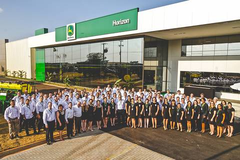 	Fotografia de grupo com todos os funcionários e diretores em frente a fachada da loja Horizon John Deere de Cambé.'