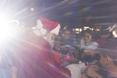 Papai Noel distribui balas a crianças em foto institucional da Cooperativa Sicoob Norte do Paraná.'