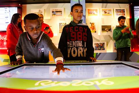 	Fotografia institucional de um garoto interagindo com painel de informações no Museu Itinerante dos Jogos Olímpicos que teve passagem por Londrina.'