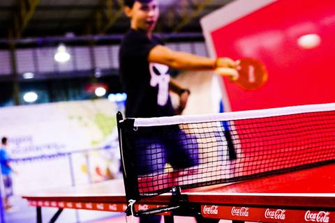 Fotografia esportiva de atleta enquanto se diverte em uma mesa de Pingue Pongue nos Jogos Escolares da Juventude.'