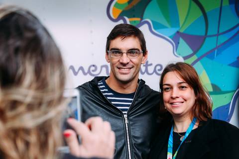 Mulher usa smarthphone para fotografar amiga ao lado do atleta-embaixador Bradesco Seguros Giba, evento realizado no centro de Londrina.'