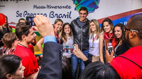 Jogador de vôlei Giba entre suas fãs em pose para fotografia de eventos no Museu Itinerante sobre Jogos Olímpicos.'