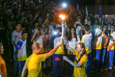 O atleta Luciano Pagliarini em fotografia de esportes com a Tocha Olímpica no Ginásio Moringão em Londrina.'
