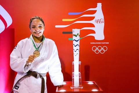 Atleta de taekwondo posa para fotografia esportiva ao lado de Tocha Olímpica dos Jogos do Rio 2016.'