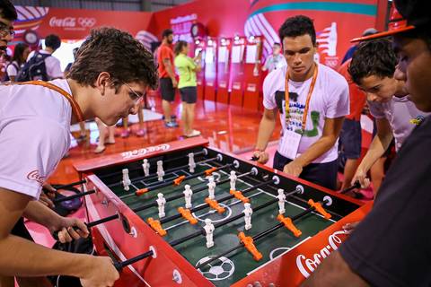 Fotógrafo de evento corporativo registra atletas brincando em mesa de Totó ou Pebolim.'