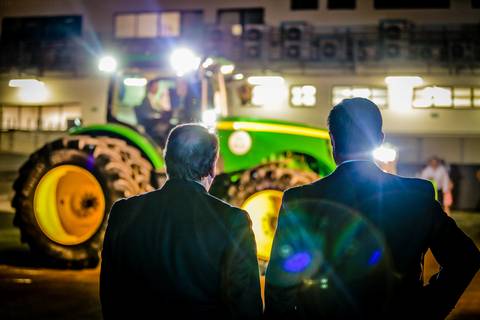Fotógrafo de eventos corporativo Roberto Custodio registra dois homens observando trator.'