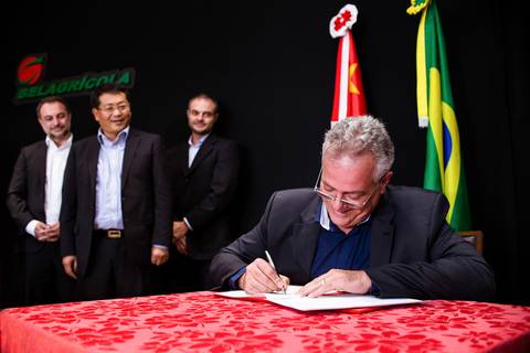 Fotografia de evento corporativo onde o executivo João Andreo Colofatti assina termo de compra e venda da empresa Belagrícola de Londrina.'
