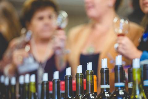 Detalhe em fotografia de evento corporativo de vários bicos de garrafas de vinho.'