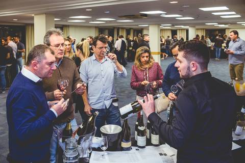 Fotografia mostra vários empresários em volta de um sommelier, fotógrafo profissional em eventos corporativos de londrina foi preciso no clic.'