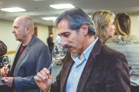 Fotógrafo profissional de Londrina especialista em fotografia de eventos corporativo mostra enólogo cheirando uma taça de vinho branco.'