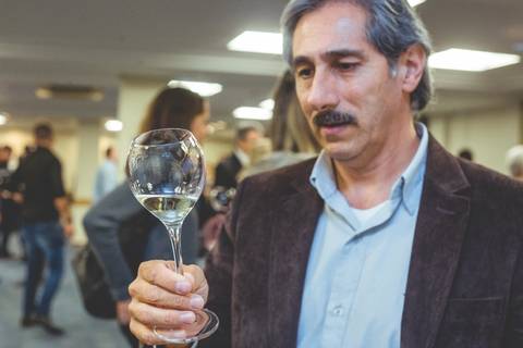 Enólogo observa uma taça de vinho branco em fotografia feita por fotógrafo profissional em Londrina-Pr. '