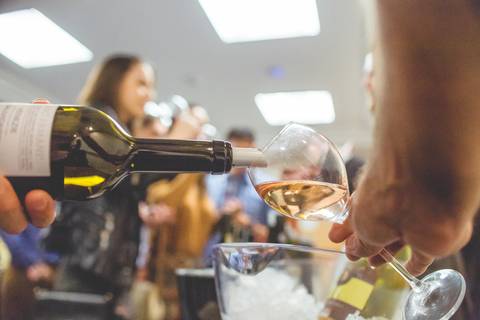 Sommelier enche uma taça de vinho em fotografia de evento corporativo durante degustação de vinhos em Londrina-Pr.'