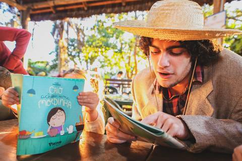 Homem lê para uma criança em fotografia de evento corporativo em Londrina-PR.
'