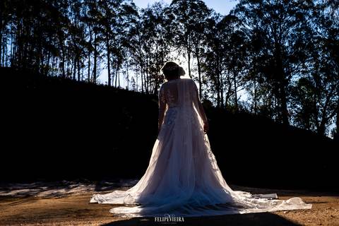 Silhueta de noiva em ensaio externo em Pedra Azul com céu azul ao fundo e detalhes de árvores'