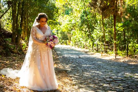 Retrato de noiva em meio a árvores com detalhes do vestido e buquê em ensaio externo pós-wedding'