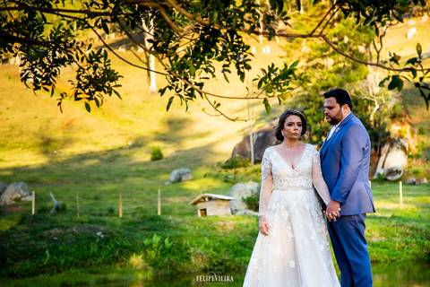 Noivos de mãos dadas em ensaio externo com paisagem ao fundo'