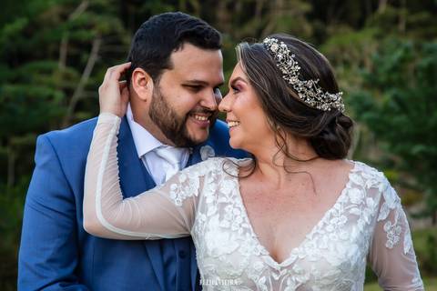 Noivos sorrindo enquanto abraçados com detalhe do vestido da noiva em ensaio externo de casamento'