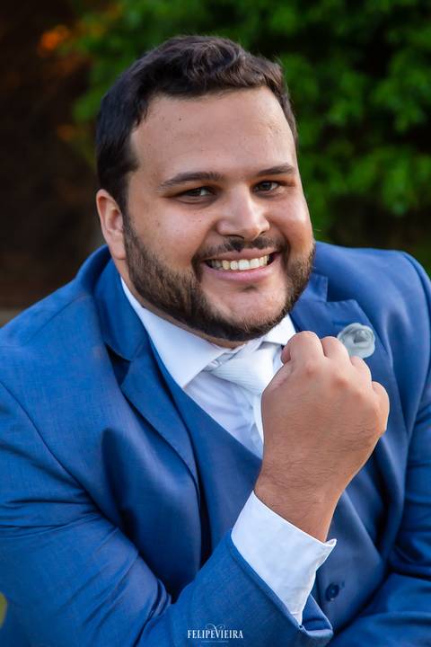 Retrato de noivo sorrindo com detalhes do terno em ensaio externo '