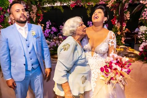 Noivos sorrindo em foto com avó em festa de casamento em guarapari '