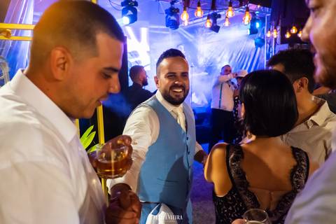 Noivo sorrindo em festa com convidados felizes e com show de luzes em casamento'