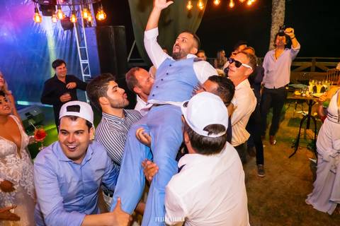 padrinhos e convidados jogando noivo para cima no ar felizes e animados em festa de casamento'