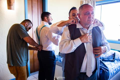 Noivo e seu pai se arrumando antes do casamento com seus padrinhos'