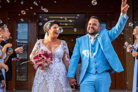 Noivos saindo da igreja e comemorando felizes o casamento em guarapari '