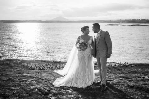 Foto preto e branco de noivos em ensaio externo pós casamento em frente ao mar'