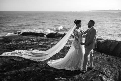 Noivos de mãos dadas em frente ao mar em foto preto e branco no ensaio externo pós casamento'