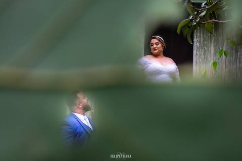 foto artística com uma folha em frente ao casal aparecendo somente o noivo e a noiva'