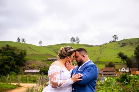 noivos diante de uma bela paisagem num dia nublado com o noivo com a mão no rosto da noiva'
