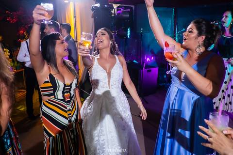 noiva na pista com madrinhas e amigas com copos na mão e dançando ao som do dj'