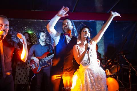noivos no palco da banda da festa de casamento cantando e dançando e se divertindo'